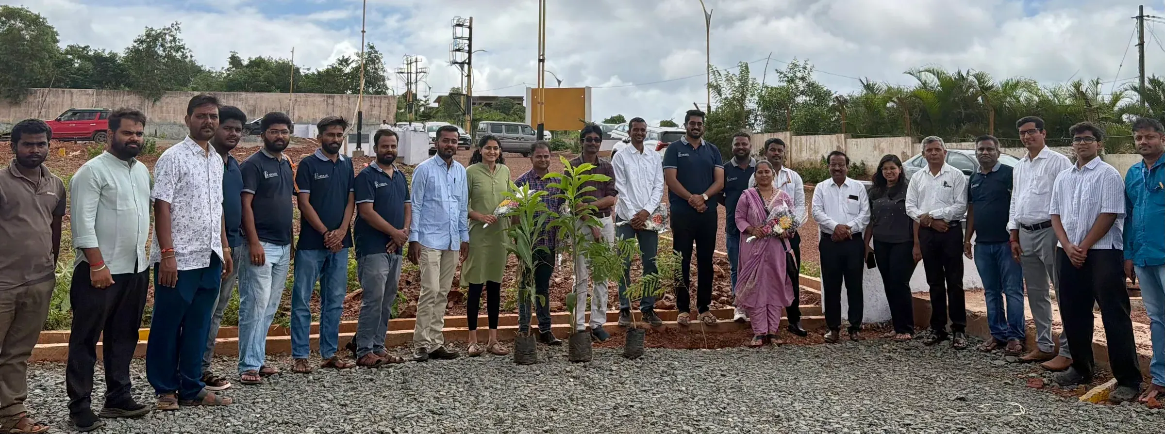 The Apollo team and guests gathered around newly planted saplings at a planting drive
