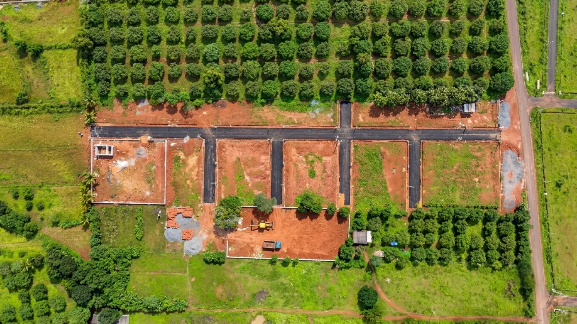 Top-down view of a newly laid plot layout with tarred roads amid orchards